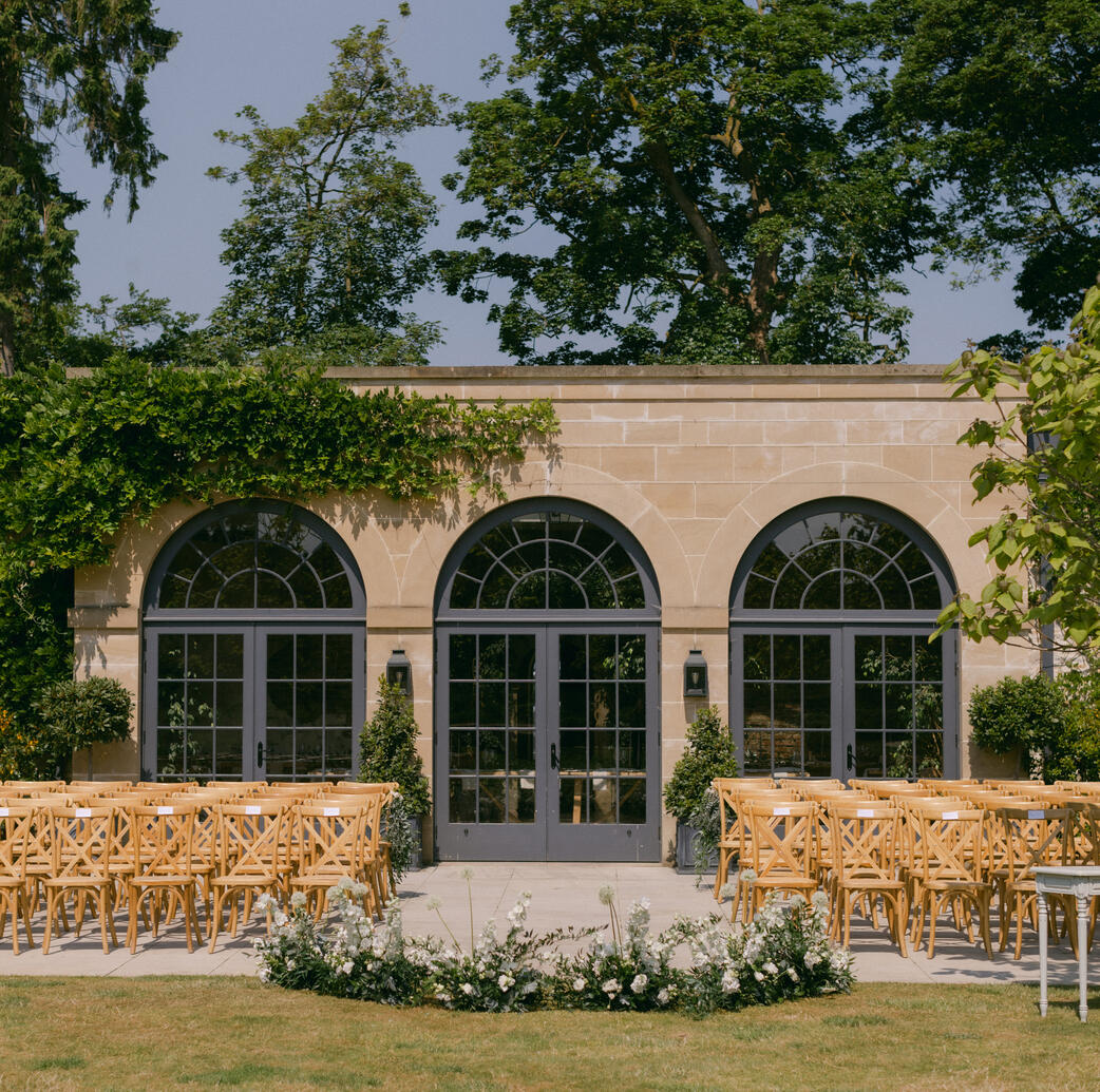 Outdoor ceremony at The Fig House at Middleton Lodge An outdoor wedding ceremony set up at The Fig House dressed with a meadow of flowers