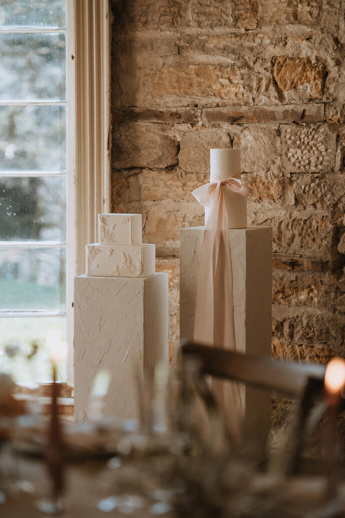 Wedding cakes displayed on plinths styled with silk ribbon