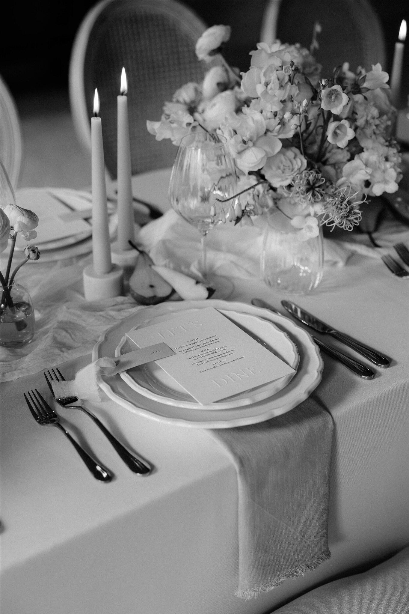 Wedding styling at Halton Grove Weddings in Northumberland. Place setting with dove grey plate, muslin napkin and antique cutlery. There is also a small bud vase with blue & lilac flowers